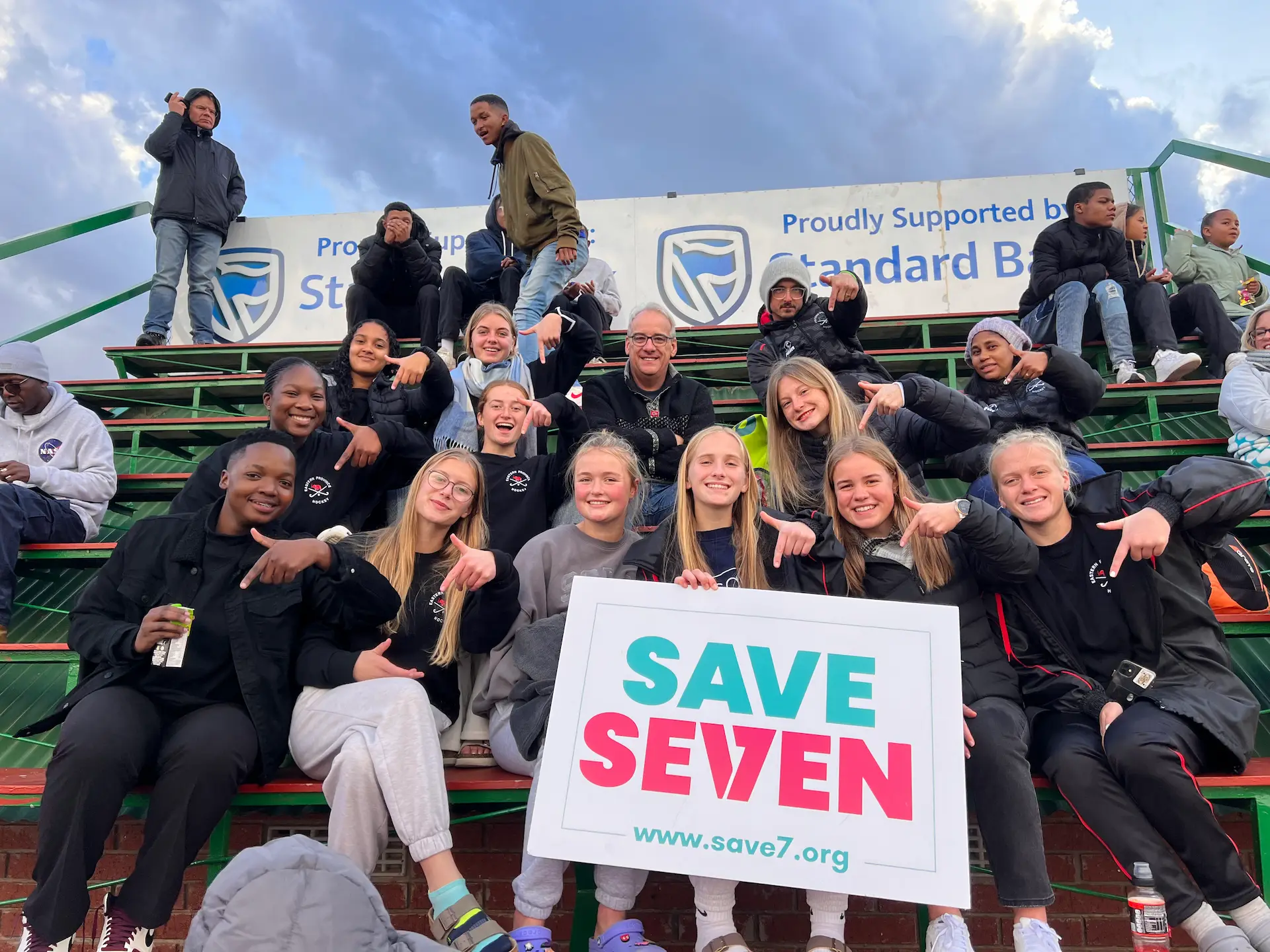 SaveSeven team members holding a sign saying 'Save7'